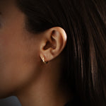 Huggie earrings in 18K gold, worn on the ear