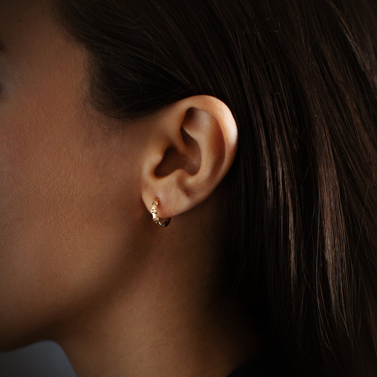 Huggie earrings in 18K gold, worn on the ear